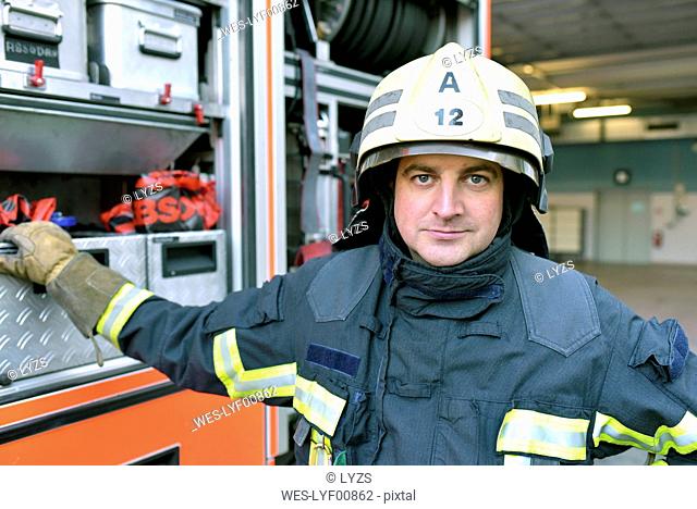 Portrait of confident firefighter in front of fire engine