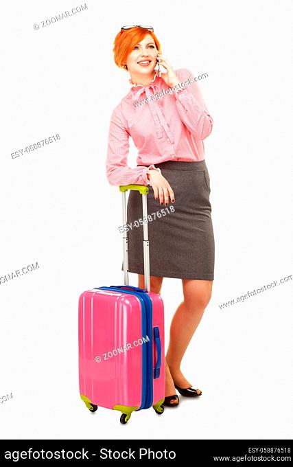 Business woman in business trip with a suitcase on wheels speaking mobile and smiling , isolated on white background