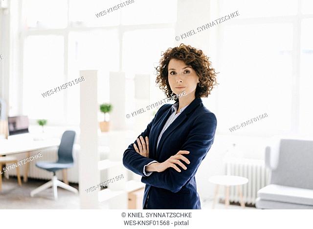 Businesswoman standing in her office with arms crossed