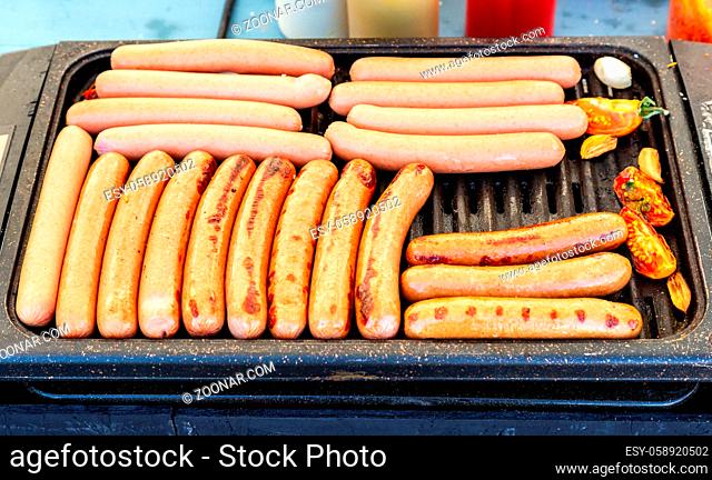 Delicious sausages on a metal grid grilling over hot coals for a picnic lunch on a summer vacation