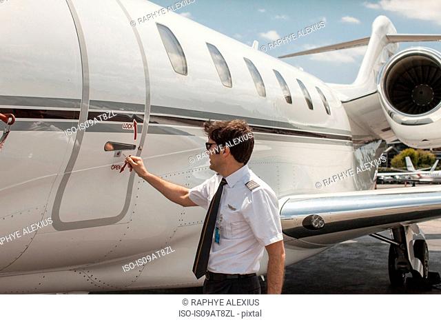 Male private jet pilot locking plane door at airport
