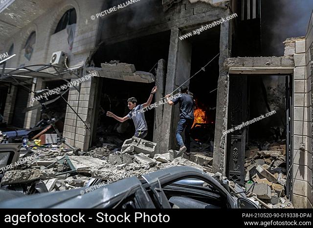 20 May 2021, Palestinian Territories, Gaza City: Palestinians inspect the damages in a building after it was hit during Israeli airstrikes