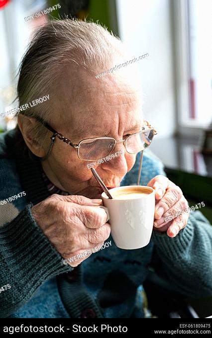 84 yo white woman drinking a cup of coffee, Flanders, Tienen, Belgium