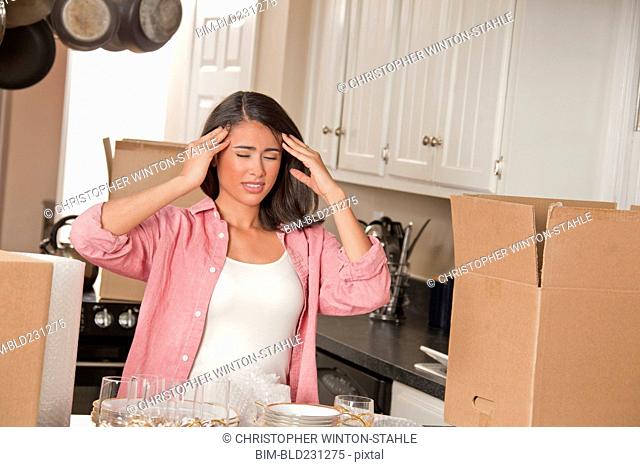 Frustrated Smiling Hispanic in kitchen with cardboard boxes