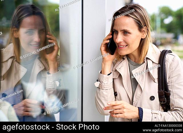 Medium shot of woman and her reflection on shop window