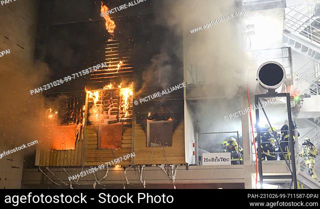 PRODUCTION - 12 October 2023, Lower Saxony, Brunswick: Firefighters extinguish a burning wooden façade during a research project at the Center for Fire Research...