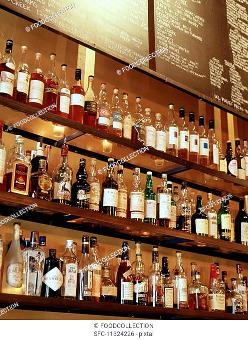 Bottles of spirits on a glass shelf behind a bar