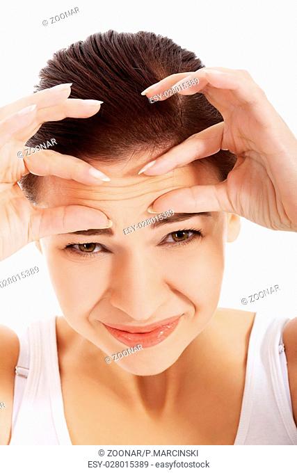 Young beautiful woman is checking her wrinkles on forehead