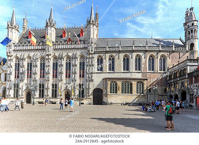 Bruges, Belgium - July 7, 2017: Tourists walking and taking pictures in front of the Provinciaal Hof in the market square in the center of Bruges