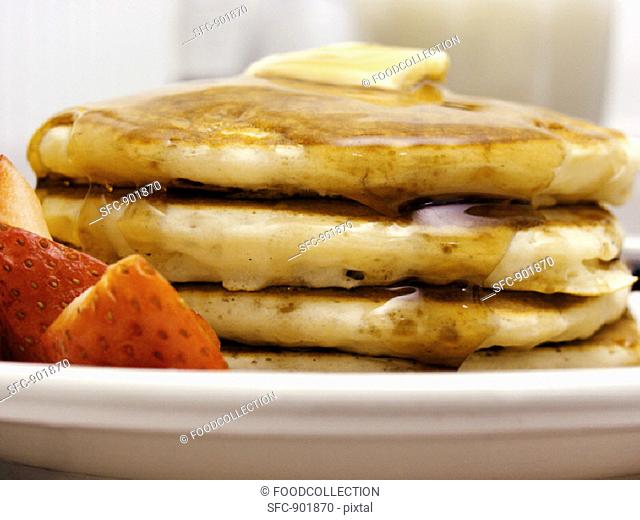 A Stack of Pancakes with Maple Syrup and Strawberries