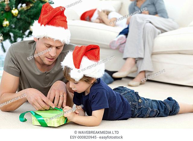Father and son unwrapping a present lying on the floor in the living room