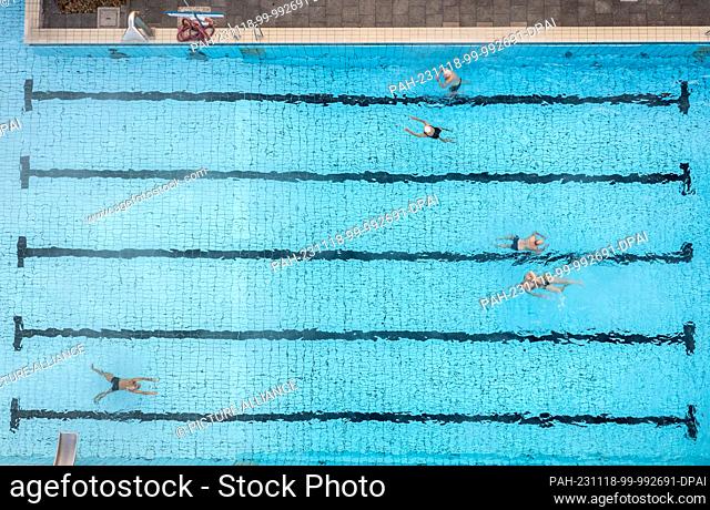 PRODUCTION - 17 November 2023, North Rhine-Westphalia, Oelde: Five bathers swim their lengths in the 28-degree swimming pool at an outside temperature of 1...