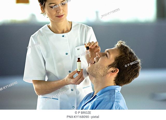 Female doctor giving medicine drops to a male patient