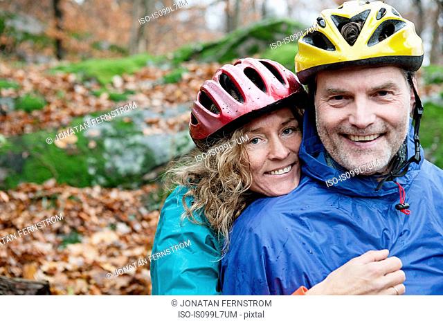 Portrait of mature couple wearing cycling helmets in forest