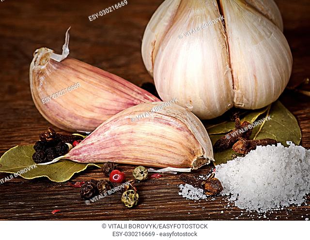 Clove of garlic and spices pile of salt on wooden table
