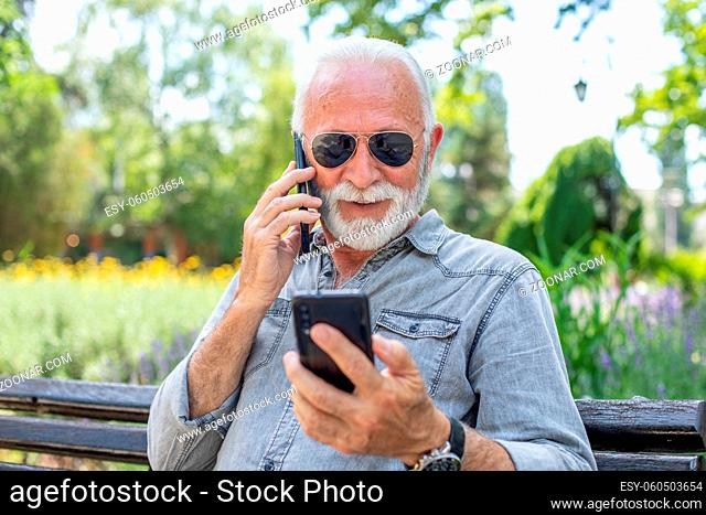 Old man compare two smartphones