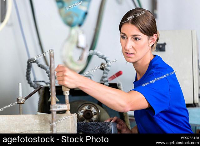Female stonemason adjusting workpiece in polishing machine