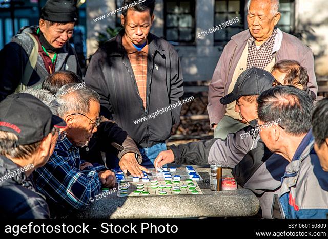 New York, United States of America - November 17, 2016: Group of Chinese men playing a board game in Columbus Park in Chinatown