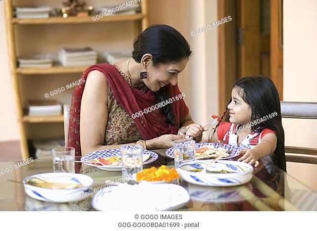 Woman helping granddaughter eat