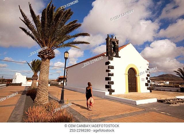 Woman posing in front of the Ermita de San Antonio de Padua parish church, Lajares, Fuerteventura, Canary Islands, Spain, Europe