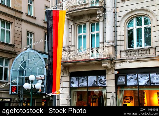 National flag of Germany next to a building in Wiesbaden city center, Hesse, Germany. Wiesbaden is one of the oldest spa towns in Europe