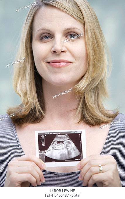 Pregnant woman holding CAT image of her belly