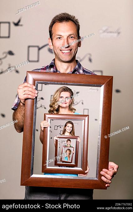 Happy father holding portrait with his family each is located inside their own frame