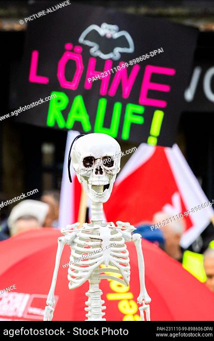 10 November 2023, Berlin: A skeleton can be seen in front of a sign reading ""Wages up!"" at a ver.di retail strike rally on Wittenbergplatz