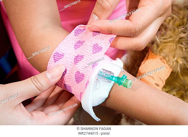 Girl having bandage put around catheter