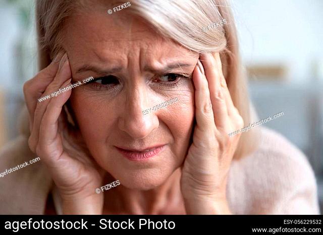 Close up woman frown face holds head with hands feels desperate, 60s female touches temples suffers from headache thinking about emotional or health problems