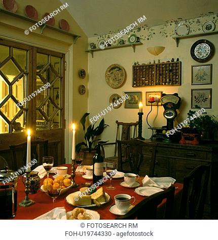 Candles in dining room with table set for dinner and glazed pine doors