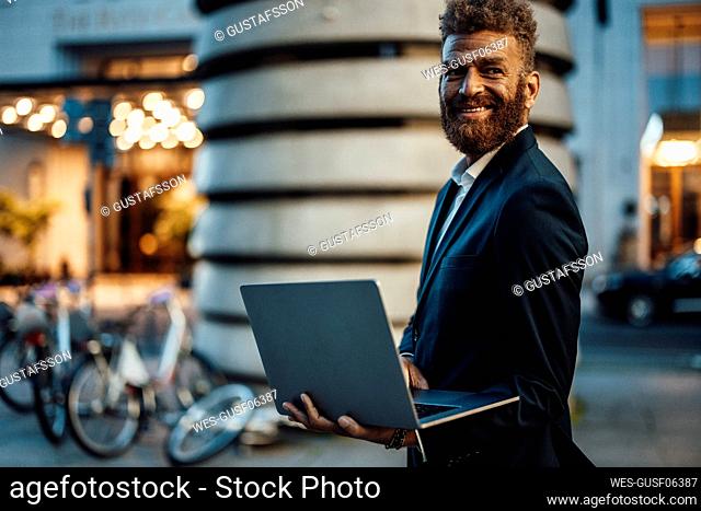 Smiling male professional holding digital tablet on street