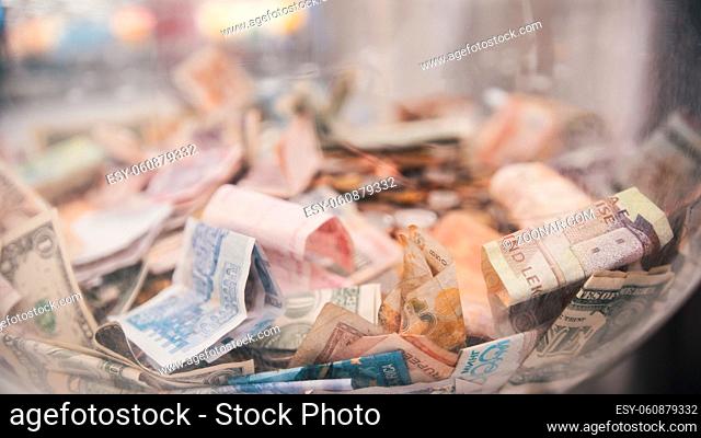 A lot of different bills - money of different countries in big glass jar, close up