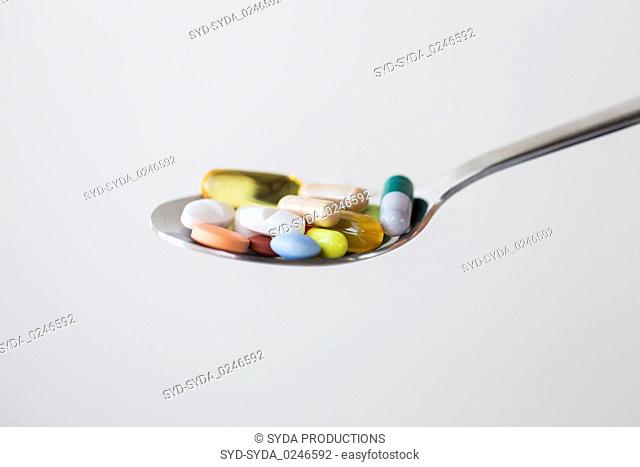 different pills and capsules of drugs on spoon