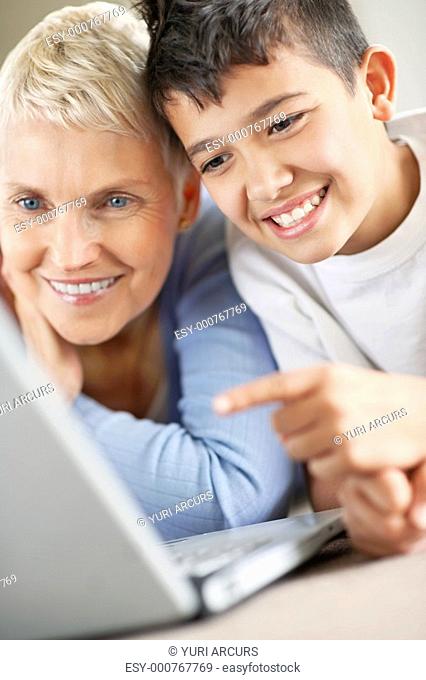 Closeup of a grandson teaching his relaxed grandmother how to surf the laptop