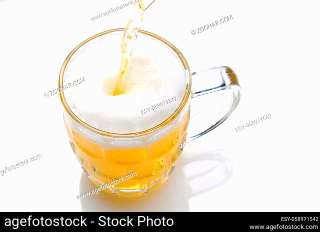 Cold beer pouring into a mug on a white background with reflection