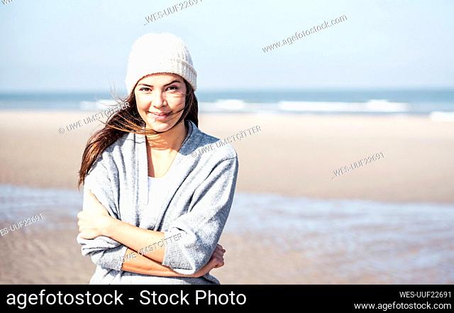 Smiling beautiful woman in cardigan sweater at beach on sunny day