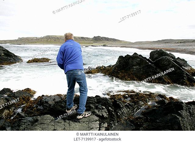 A man is fishing on the rocks by the Arctic Ocean in Vardö in the Varanger Peninsula, Norway. Vuoreija Vuorea Vardo Vardo