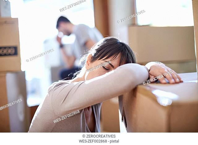 Couple moving house, woman resting on a box