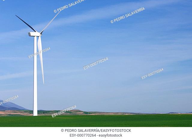 one modern windmill in a meadow with blue and cloudy sky in Pozuelo de Aragon, Saragossa, Spain