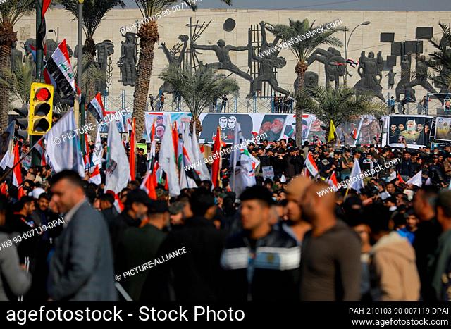03 January 2021, Iraq, Baghdad: Iraqis hold flags during a protest at Tahrir Square to commemorate the one-year anniversary of the assassination of Iranian...