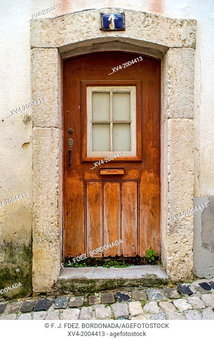 Aged door oranged in the Narrow streets around Castelo Sao Jorge. Alfama. Lisboa. Portugal. Europe