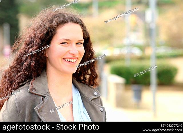 Beautiful woman with curly hair looking at camera in a park