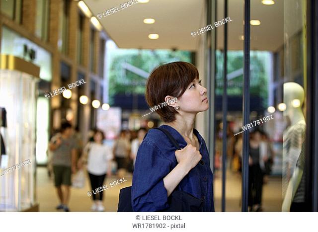 A woman in a shopping mall looking at a shop window display