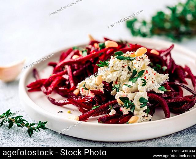 Raw beetroot spaghetti salad with soft cheese, nuts, thyme. Vegetable noodles - Fresh Beetroot Noodles with Ricotta and fresh thyme on plate