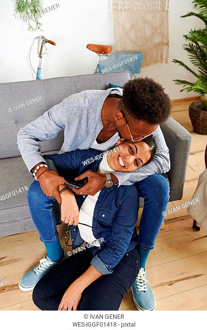 Multiethnic couple spending time together at living room, man kissing his girlfriend
