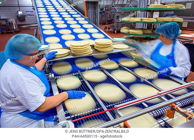 Staff check the production line that of the bases of frozen pizzas at the pizza factory of food company Dr. Oetker in Wittenburg, Germany, 08 Decemeber 2015