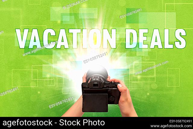Close-up of a hand holding digital camera with VACATION DEALS inscription, traveling concept