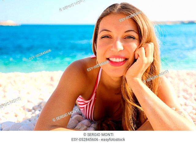 Pretty girl lying on pebbles beach. Summer holidays vacation concept