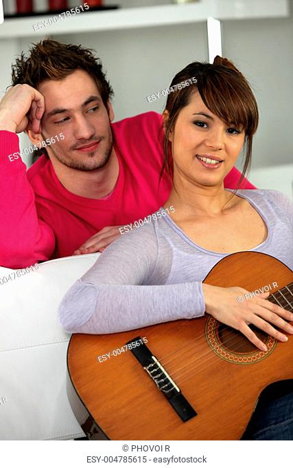 Woman with guitar sat next to boyfriend